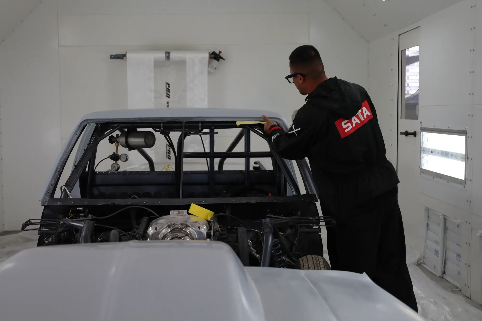 Professional paint and body shop setup with technician preparing vehicle for collision repair and repainting