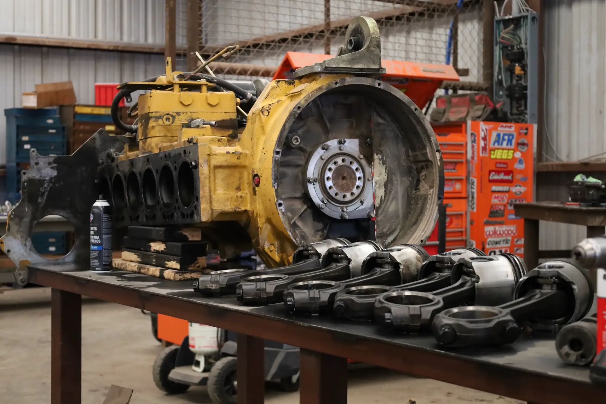 Disassembled heavy equipment engine with connecting rods and components staged on a workbench for professional repair and rebuild