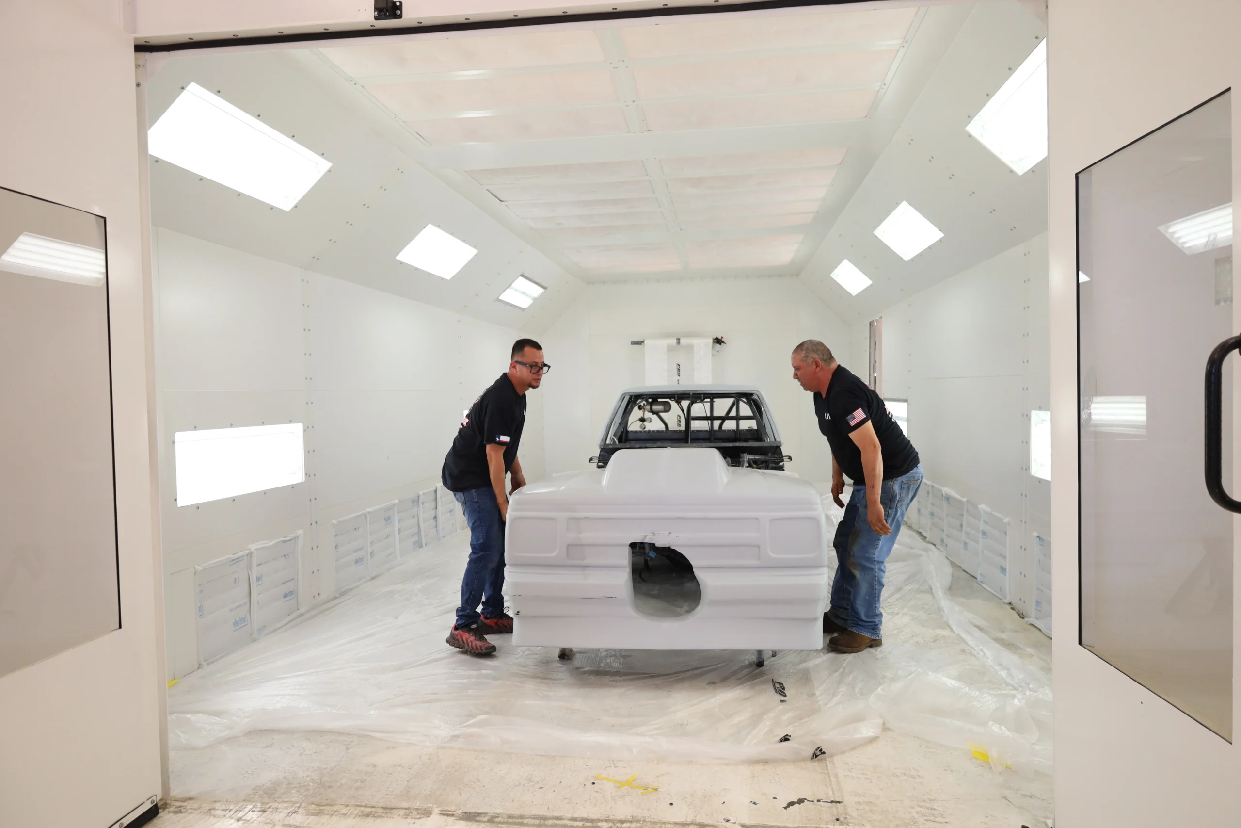 Technicians positioning a repaired vehicle body panel before refinishing at Chris’s Diesel Service in Midland, TX