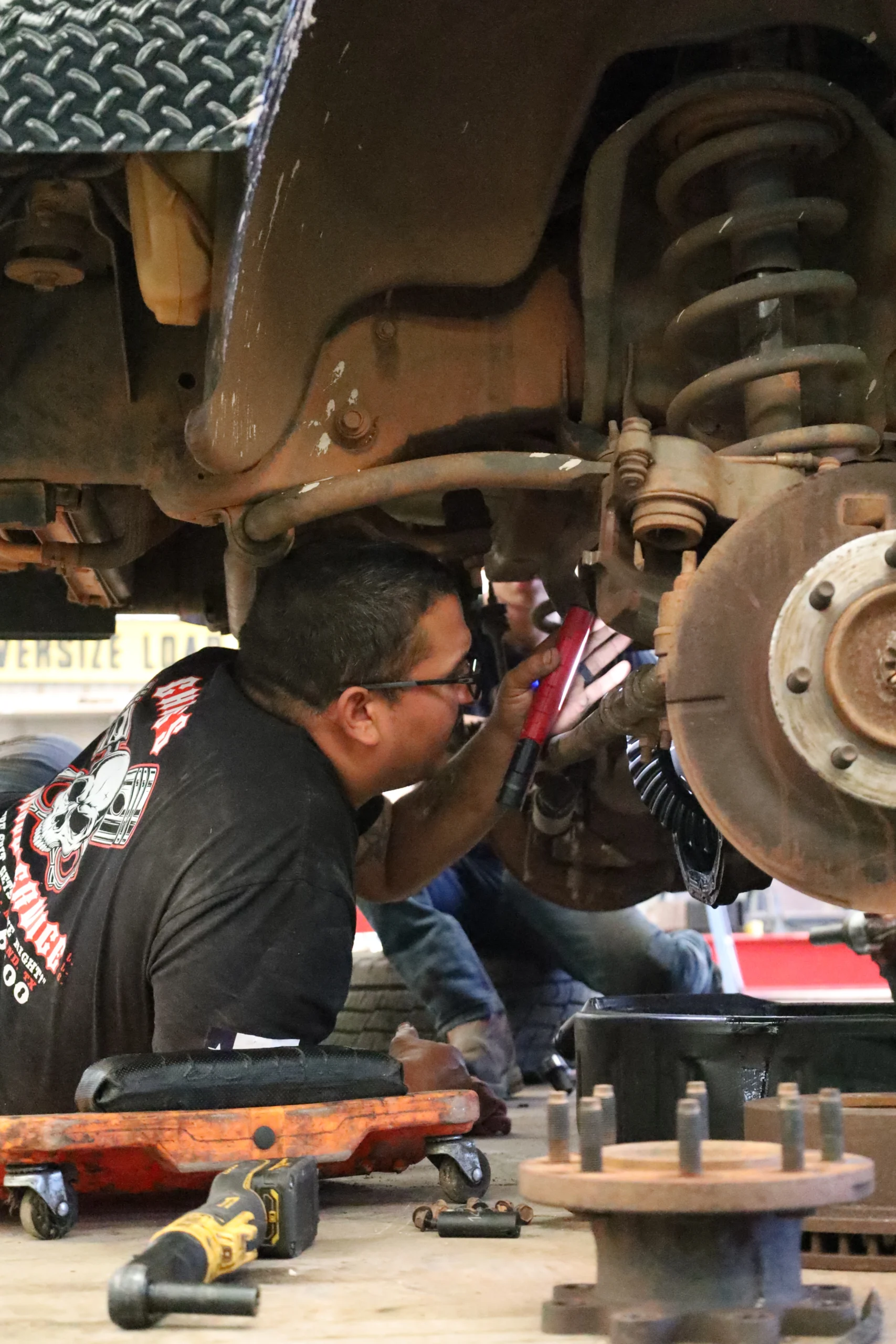 Technician inspecting brake and suspension during vehicle repair at Chris's Diesel Service in Midland TX