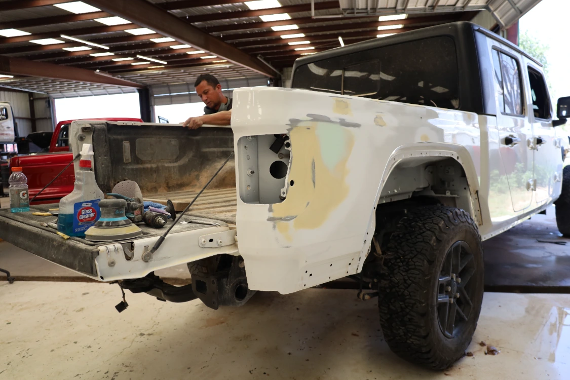 Technician repairing and sanding a damaged vehicle body panel during car dent repair at Chris's Diesel Service in Midland, TX