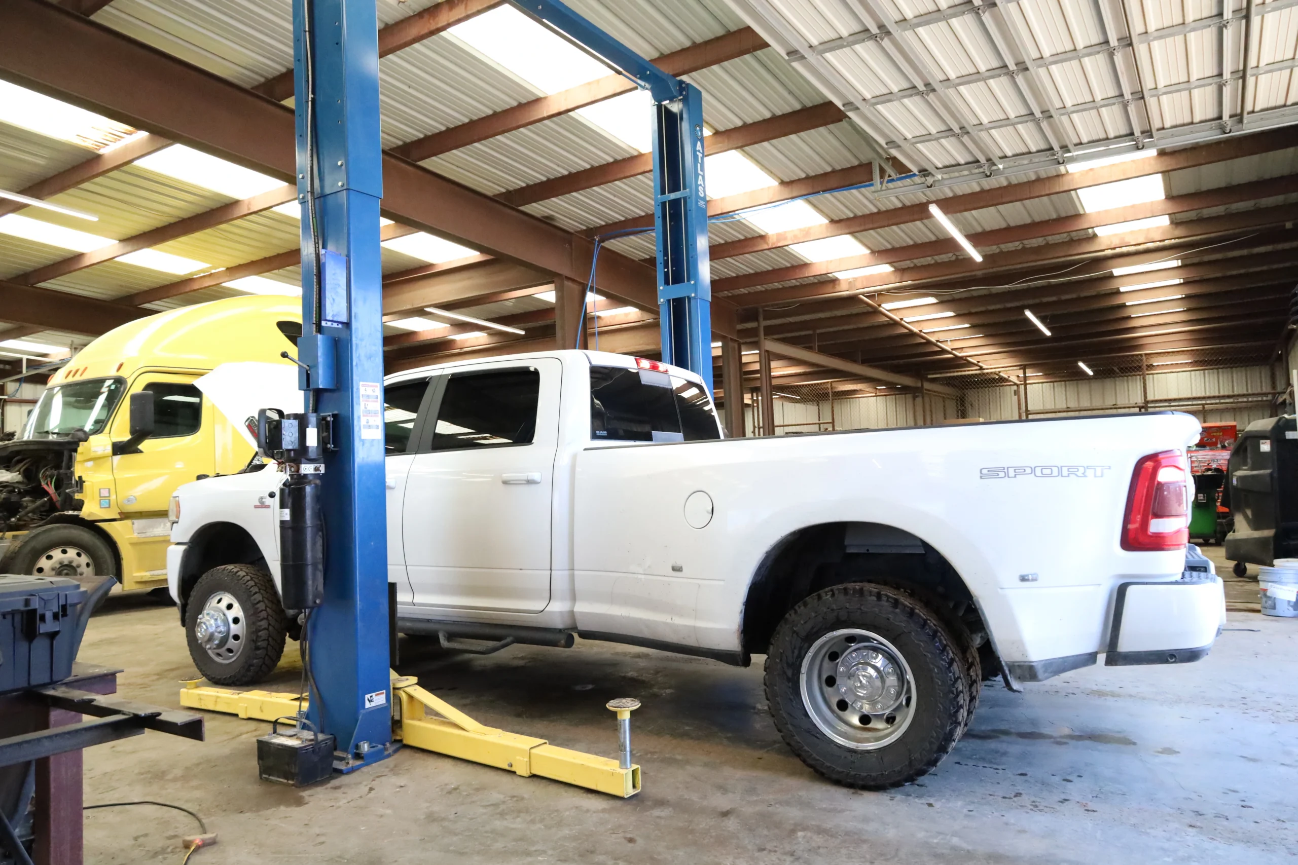 Fleet vehicle repair on Ram 2500 heavy-duty pickup lifted inside Chris's Diesel Service shop in Midland TX