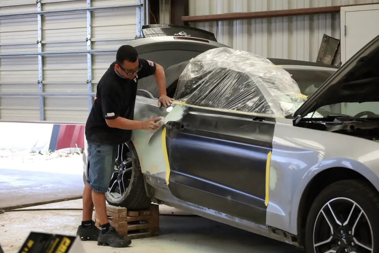  Technician sanding and prepping a vehicle panel for paint at Chris's Diesel Service in Midland, TX