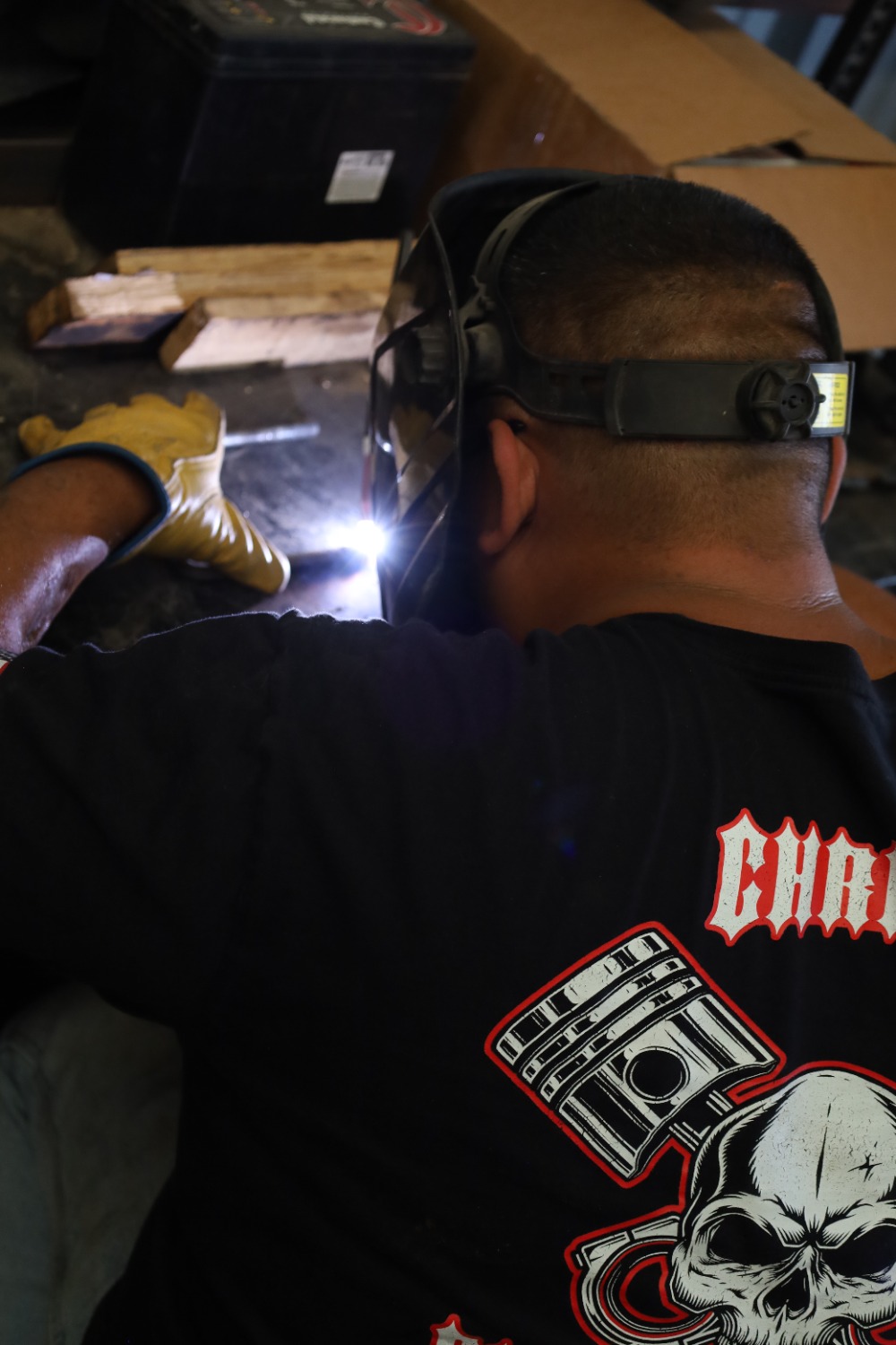 Welder in a protective hood making a weld at a workbench at Chris's Diesel Service in Midland, Texas