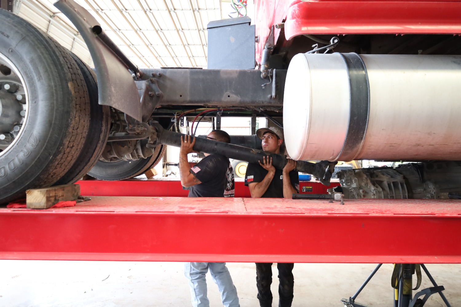 Two technicians installing a driveshaft on a heavy duty diesel truck at Chris's Diesel Service in Midland, Texas