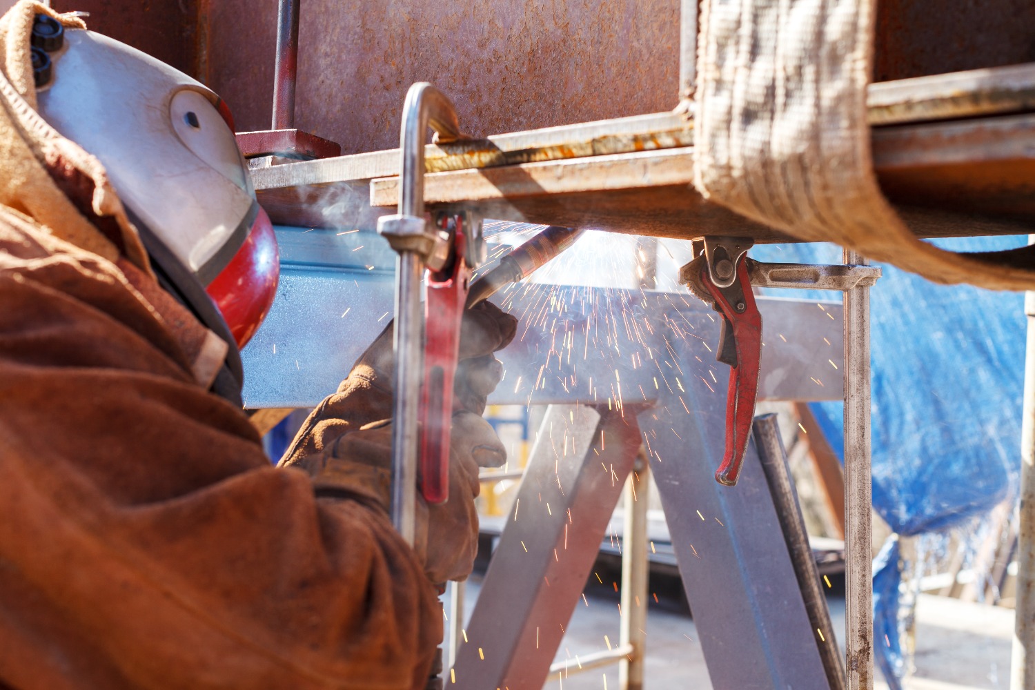 Welder in full protective gear making a structural weld on clamped steel sections in Midland, Texas